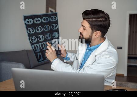 Junger männlicher Arzt diskutiert Lunge Röntgen während der Videokonferenz auf Notebook Stockfoto