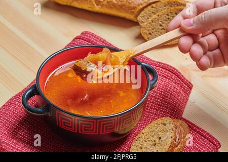 Suppe mit Brot in einer roten und schwarzen Schüssel Stockfoto