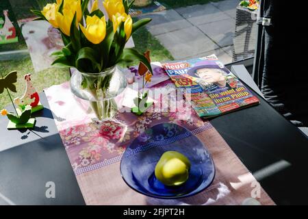 Fehmarn, Deutschland. April 2021. Auf einem Tisch in einer Markise liegt eine Zeitschrift, auf der sich auch Blumen und Früchte befinden. Quelle: Frank Molter/dpa/Alamy Live News Stockfoto