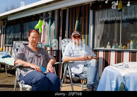 Fehmarn, Deutschland. April 2021. Die Dauercamper Claudia (l) und Dietmar Runold aus Langenhagen sitzen auf der Terrasse ihres Stellplatzes. Das Ehepaar ist seit fast 30 Jahren auf dem Campingplatz am Wulfener Hals zu Gast. (To dpa: 'Campings long for Opening despite permanent campers') Quelle: Frank Molter/dpa/Alamy Live News Stockfoto