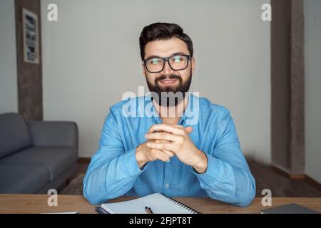 Smart man Freiberufler in Brillen Blick auf die Kamera während des Sitzens Am Schreibtisch Stockfoto