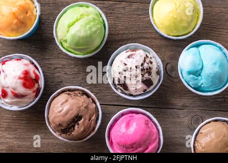 Eiscreme-Sortiment. Verschiedene Eiscreme oder italienisches Eis auf Holzhintergrund, Nahaufnahme. Gefrorener Joghurt in kleinen Tassen - gesundes Sommerdessert. Stockfoto