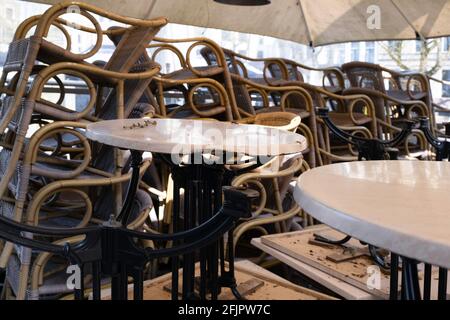 Stühle und Tische übereinander unter einer Restaurantmarkise gestapelt. Es ist wegen der Sperrung aufgrund von Corona in den Niederlanden geschlossen Stockfoto