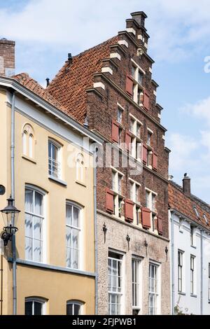 Bunte façades historischer gelber, roter und weißer Häuser in Deventer. Das mittlere Backsteinhaus hat einen schönen dreieckigen abgestuften Giebel Stockfoto