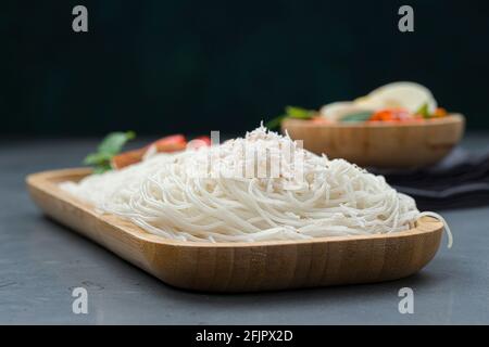 Ideyappam oder Noolappam, südindisches Frühstücksartikel aus rohem Reis Die in einer hölzernen Servierunterlage mit Ei angeordnet ist masala als gute Kombination Stockfoto