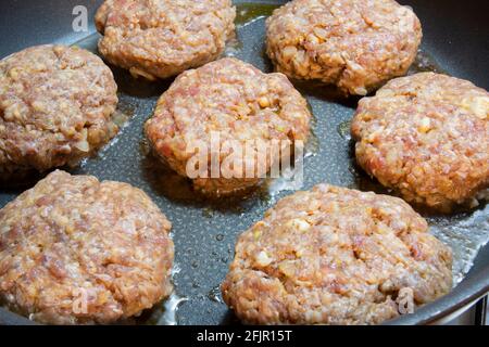 Roh. Hausgemachte Burger-Fleischbällchen werden in einer gusseisernen Pfanne gekocht. Selective Focus Burger Frikadellen. Stockfoto