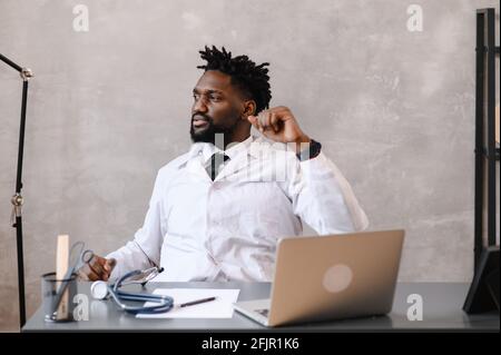 Lustig gelangweilt bei der Arbeit afroamerikanischen Arzt Arbeitnehmer Einschlafen am Schreibtisch, Mitarbeiter schlafen am Arbeitsplatz in der Nähe von Laptop Gefühl überarbeiteter Konzept Stockfoto