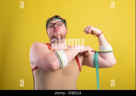 Lustige fette Mann in Sportbekleidung misst das Volumen seiner Arm Stockfoto