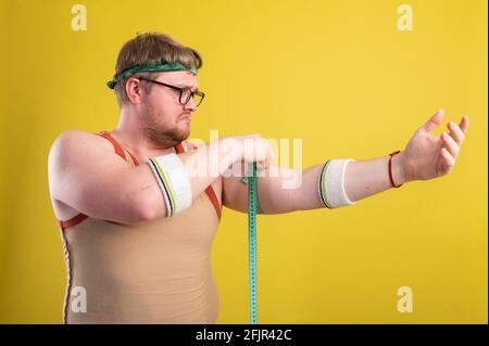 Lustige fette Mann in Sportbekleidung misst das Volumen seiner Arm Stockfoto