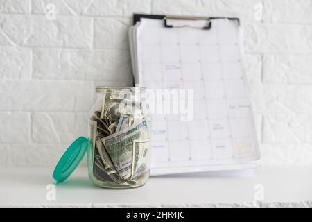 Faltet Geld in einem Glas auf einem weißen Holzhintergrund. Der Ort des Hintergrundbildes für Text. Stockfoto