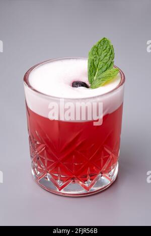 Roter Cocktail mit Minze Clover Club auf grauem Hintergrund. Stockfoto