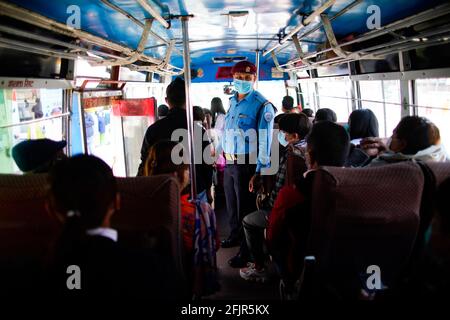 Kathmandu, Nepal. April 2021. Ein Verkehrspolizist inspiziert einen öffentlichen Bus, um sicherzustellen, dass Menschen angesichts der Besorgnis über die Ausbreitung der zweiten Welle der Coronavirus-Krankheit in Kathmandu, Nepal, am Montag, dem 26. April 2021, Masken tragen. Kredit: Skanda Gautam/ZUMA Wire/Alamy Live Nachrichten Stockfoto