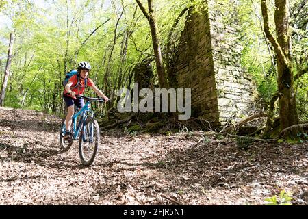 Der Junge fährt im Frühjahr mit dem Dirtbike Landschaft bergab Stockfoto