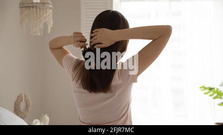 Millennial Mädchen mit Kamm Bürsten lange gerade Haare im Schlafzimmer Stockfoto