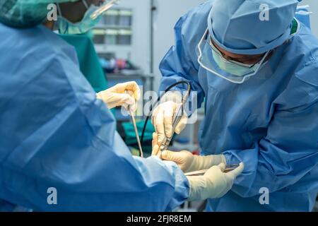 Medizinisches Team von Chirurgen und Assistent im Krankenhaus tun orthopädische Chirurgie. Operationssaal mit Elektrokautergeräten für Herz-Kreislauf-Erkrankungen Stockfoto