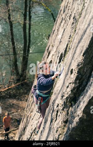 Die junge Klettererin konzentriert sich auf ihren nächsten Schritt auf der Kletterroute. Stockfoto