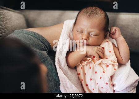 Kaukasisches neugeborenes Mädchen, das in den Händen ihrer Mutter schläft und sich wohlfühlt Und sicher Stockfoto