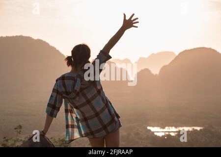 Glückliches schlankes Hipster-Mädchen steht am Aussichtspunkt gegen Meer und Inseln bei Sonnenaufgang. Phang Nga Bay, Thailand Stockfoto