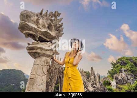 Frau Tourist auf dem Hintergrund der erstaunlichen riesigen Drachenstatue auf Kalkstein Berggipfel in der Nähe Hang Mua Aussichtspunkt am nebligen Morgen. Beliebter Tourist Stockfoto