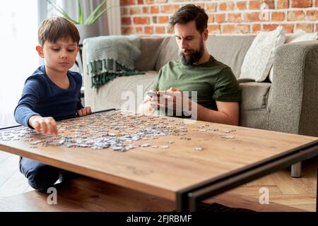 Junge Lösung Puzzle während Vater mit Stockfoto