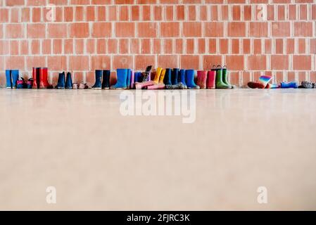 Regenstiefel aus Gummi auf dem Boden am Eingang einer College-Klasse, ohne jemand, mit Platz für Text. Stockfoto