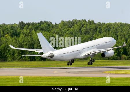 Passagierflugzeug starten vor dem Hintergrund eines Grüns Wald auf einer Landebahn Stockfoto