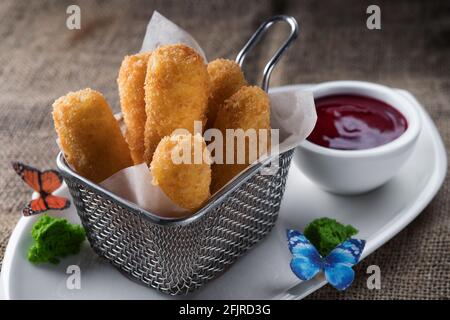 Nuggets mit Sauce auf einem weißen Teller, in einem Metallkorb Stockfoto
