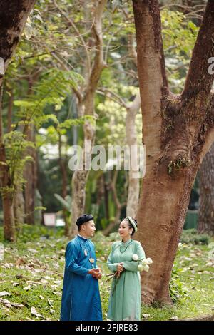 Glückliche Braut und Bräutigam in traditionellen vietnamesischen Kostümen im Gespräch parken Sie nach der Hochzeitszeremonie Stockfoto