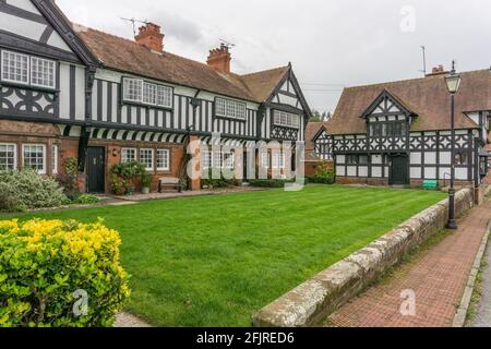 Attraktive rote Backsteinhäuser und Fachwerkhäuser im Tudor-Stil, die um einen Gemeinschaftsgarten im Dorf Thornton Hough, Wirral, Großbritannien, gebaut wurden Stockfoto