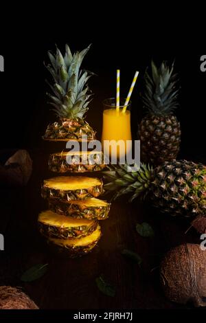 Ananas fliegend in der Luft, in Scheiben mit Saft geschnitten Glas und Ananas im Hintergrund Stockfoto