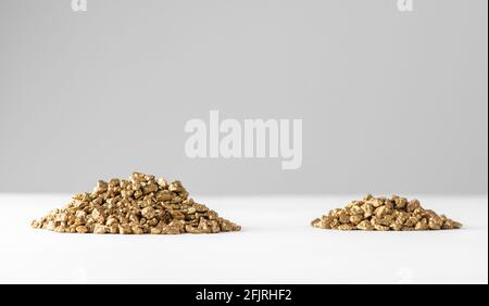 Zwei Haufen goldener Nuggets auf weißem Hintergrund Stockfoto