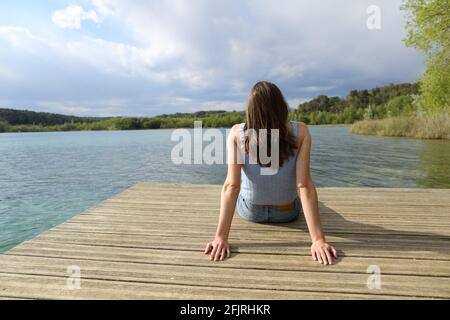 Rückansicht Porträt einer Frau, die entspannt in einem sitzt lake Pier im Sommerurlaub Stockfoto