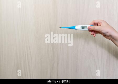 Das Thermometer ist ein Zeiger mit einer erhöhten Temperatur. Demonstriert in der Hand. Stockfoto