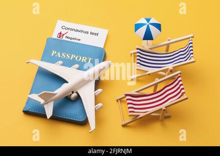 Pass, Coronavirus-Testergebnisse, Spielzeugflugzeug und Sonnenliegen auf gelbem Hintergrund, modernes Flugreisekonzept. Stockfoto