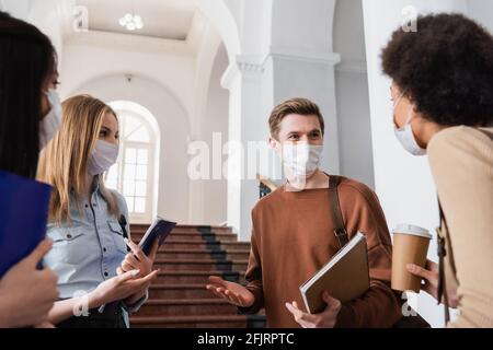 Multiethnische Studenten in Schutzmasken sprechen in der Universität Stockfoto