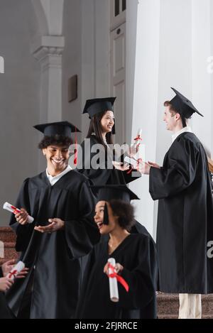Asiatischer Absolvent im Gespräch mit einem Freund an der Universität Stockfoto