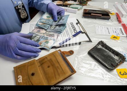 Spezialisierter Polizist notiert Dollar Banknote Referenz eines Raubes, konzeptuelle Bild Stockfoto