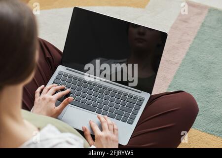 Rückansicht einer jungen Frau, die auf dem Laptop tippt und arbeitet Online, während man im Zimmer sitzt Stockfoto