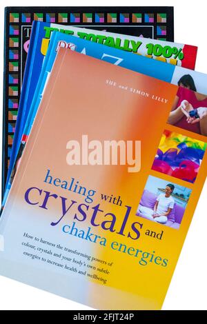 Stapel von Büchern mit Heilen mit Kristallen und Chakra-Energien Buch oben auf weißem Hintergrund Stockfoto