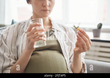 Nahaufnahme einer Schwangeren, die Glas mit Wasser hält und trinkt Vitamine am Morgen Stockfoto