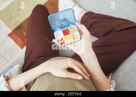 High-Angle-Ansicht der Schwangeren Frau Holding Box mit Vitaminen Und Pillen, während Sie auf dem Sofa sitzen Stockfoto