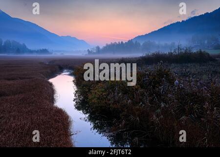 Naturschutzgebiet des Sees Zelenci, Kranjska Gora, Slowenien. Neblige Triglav Alpen mit Wald, Reisen in der Natur. Schöner Sonnenaufgang mit blauem Himmel, grüner Natur Stockfoto