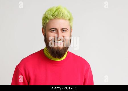 Porträt eines gutaussehenden kaukasischen Mannes mit gelben Haaren und Bart, lächelt angenehm, schaut direkt in die Kamera, ist gut gelaunt, trägt roten Pullover. Indo Stockfoto