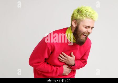 Porträt von aufgeregt glücklich gelbhaarigen Mann mit Bart, Kleider in lässigen roten Pullover, laut lachen, hören wirklich lustige Sache, hält die Hände auf dem Bauch Stockfoto