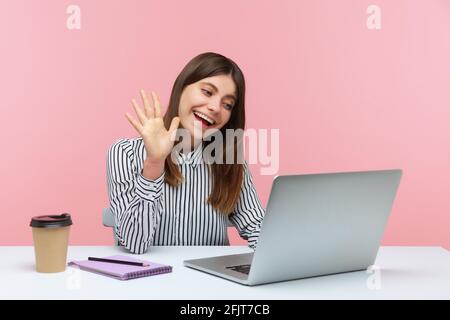 Freundliche Geschäftsfrau, die Hand auf den Laptop-Bildschirm schwenkt, mit einem Freund in einem Videoanruf spricht, Online-Konferenz im Heimbüro. Innenaufnahmen im Studio isoliert Stockfoto