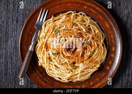 Pasta mollicata: Spaghetti mit Sardellen und gerösteten Paniermehl, Parmesankäse und Petersilie - traditionelles süditalienisches Gericht, serviert auf einem Teller o Stockfoto