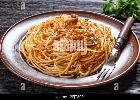 Pasta mollicata: Spaghetti mit Sardellen und gerösteten Paniermehl, Parmesankäse und Petersilie - traditionelles süditalienisches Gericht, serviert auf einem Teller o Stockfoto