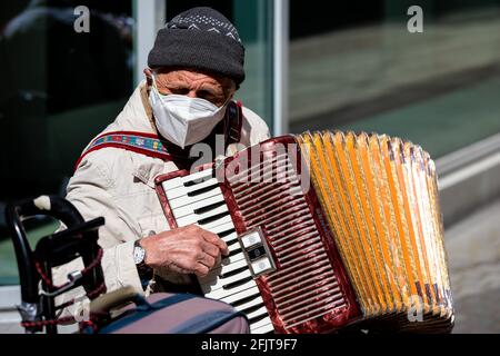 Hannover, Deutschland. April 2021. Ein Straßenmusiker in einer Mundnasenmaske spielt in der Innenstadt ein Akkordeon. Quelle: Moritz Frankenberg/dpa/Alamy Live News Stockfoto