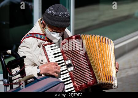 Hannover, Deutschland. April 2021. Ein Straßenmusiker in einer Mundnasenmaske spielt in der Innenstadt ein Akkordeon. Quelle: Moritz Frankenberg/dpa/Alamy Live News Stockfoto