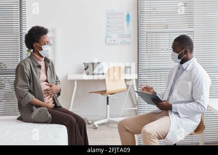 Schwanger Frau in Schutzmaske Besuch des Arztes im Krankenhaus Und sprach mit ihm Stockfoto